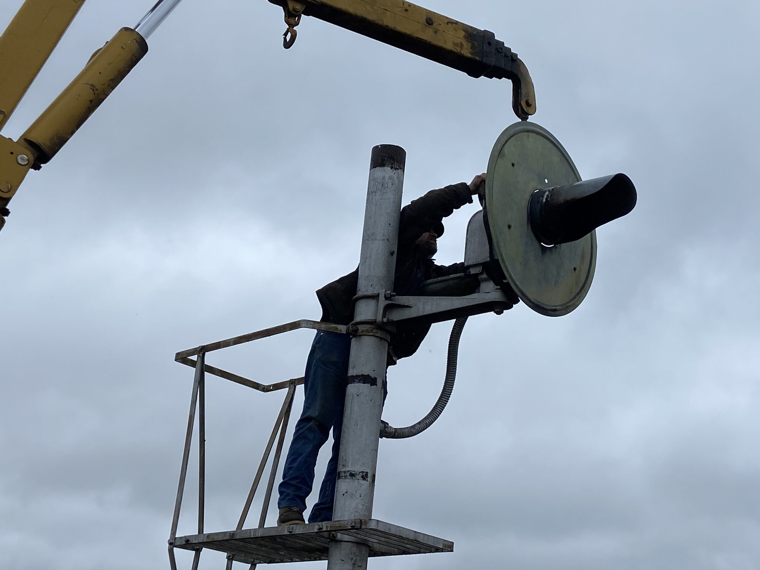 A volunteer unfastens the signal head from the mast.